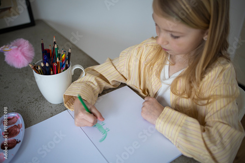 Side View of Young Girl Drawing with a Green Pencil at Home.