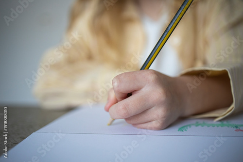 Close-up of Child's Hand Drawing with a Pencil on White Paper
