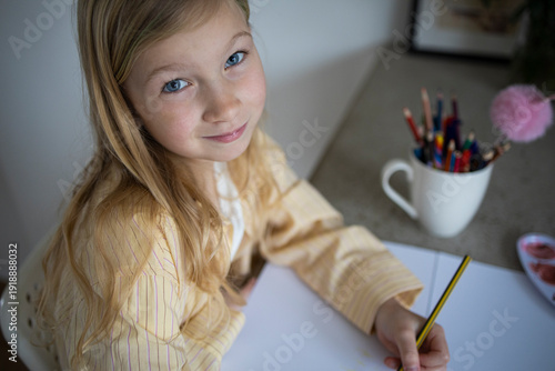 Happy Young Girl Smiling While Drawing or Doing Homework.