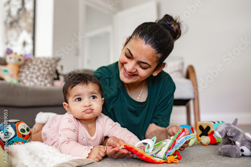 Indian mum playing with baby daughter on the carpeted floor in New Zealand