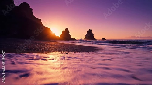 Dramatic purple sunset illuminates black sand beach with towering rock formations and crashing waves.
