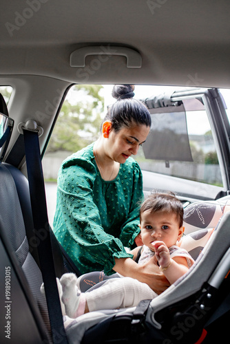 Indian mum unbuckling baby girl from car seat