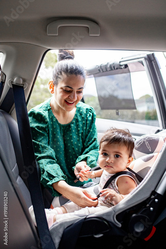 Indian mum unbuckling baby girl from car seat