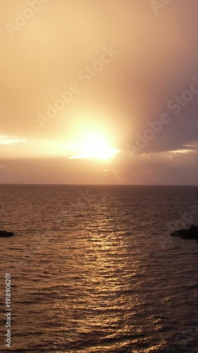Vertical drone shot of a sunset in a sea. Perspective Highlights Calm Tropical Waters Illuminated By Warm Twilight Glow