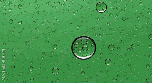 A close-up view of various clear liquid bubbles and droplets on a vibrant green surface, with one large bubble encapsulating smaller ones.
