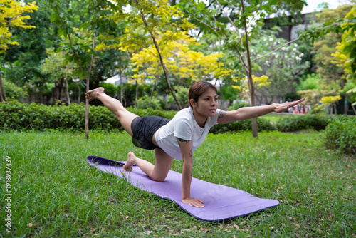 Beautiful young woman practicing Padmasana on yoga mat outdoors, space for text.