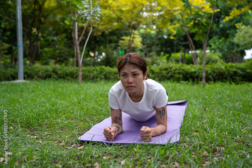Beautiful young woman practicing Padmasana on yoga mat outdoors, space for text.