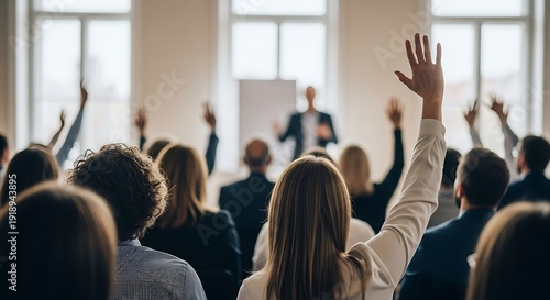 Audience raises hands in response to presenter at a business seminar