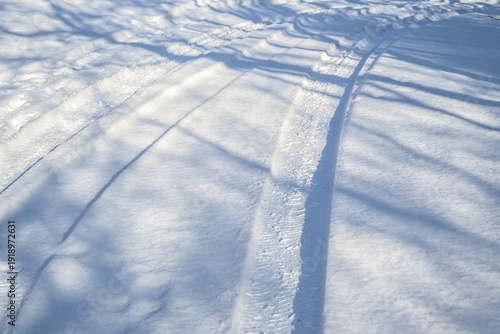 Snow-covered road with tire tracks, difficult driving conditions before the snow removal service arrives, concept for transport and traffic in the winter season, copy space