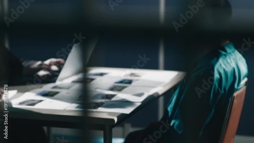 Prisoner being questioned in interrogation room beyond bars