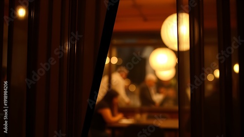noren. View through lifted noren curtain revealing warm glow and silhouettes inside restaurant. real-estate listings.