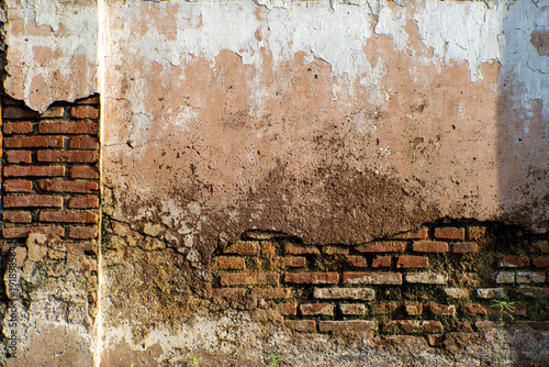 Foto Weathered red brick wall texture with peeling plaster and moisture stains