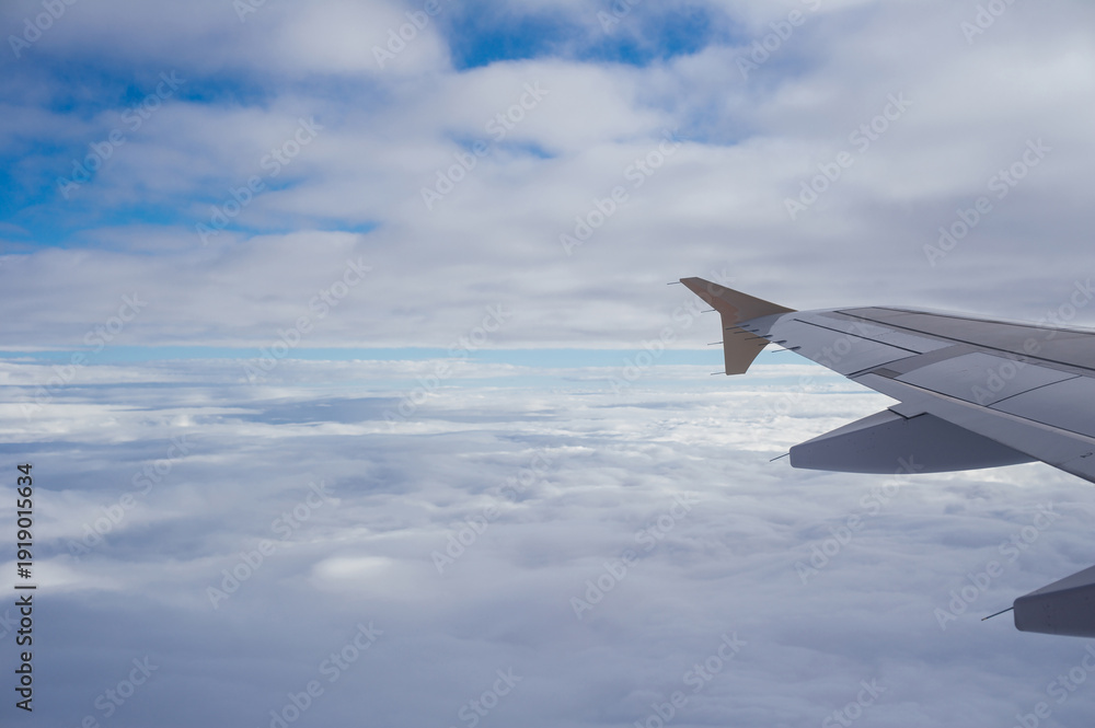 Fototapeta premium View of an airplane wing over a thick blanket of clouds