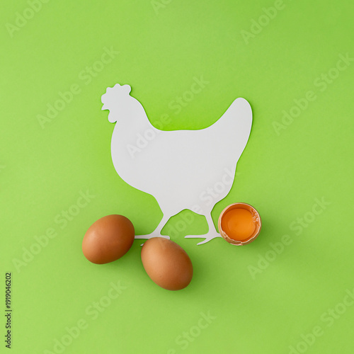 Fototapeta Creative composition of natural fresh eggs with cracked egg and yolk on light green background
