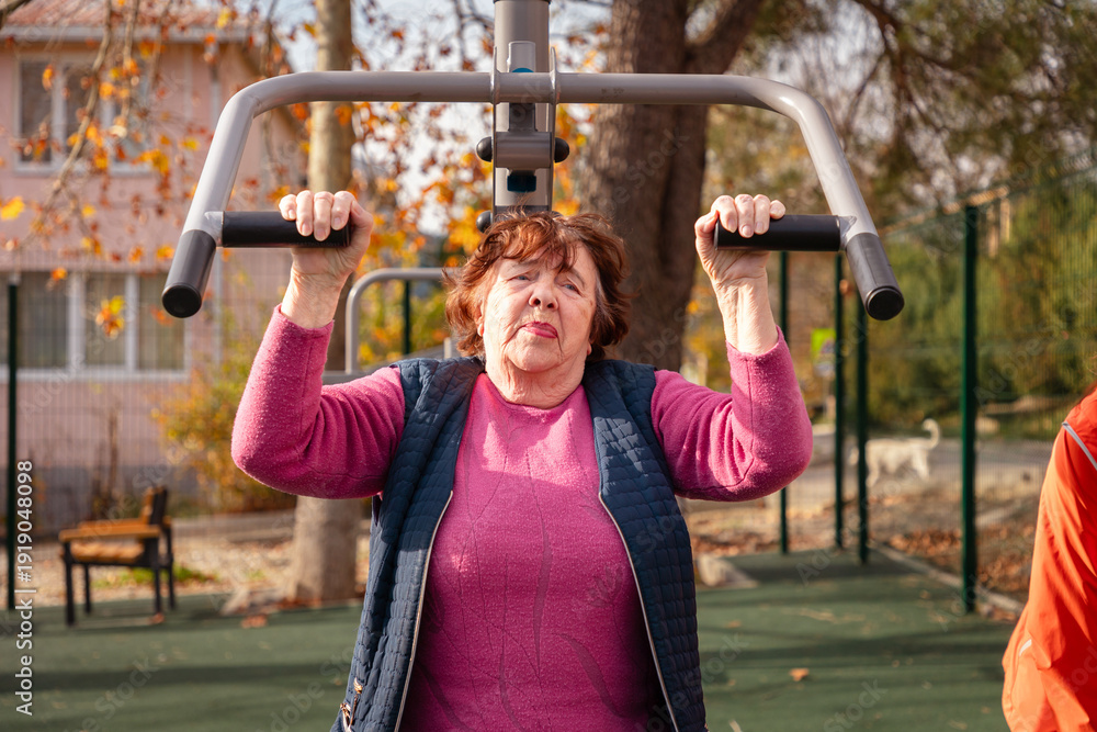 Αυτοκόλλητο Elderly Caucasian woman trains on street gym machines during post surgery recovery