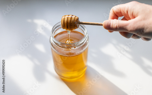 Wallpaper Mural organic honey drips from a wooden dipper into a glass jar, Torontodigital.ca