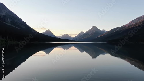 Serene lake surrounded by dark mountains reflects the sky's subtle hues