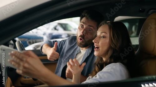 Happy Caucasian couple woman man taking selfie photo mobile phone inside new car make picture video call conference blog influencer thumb up smiling auto girl female guy male automobile social media