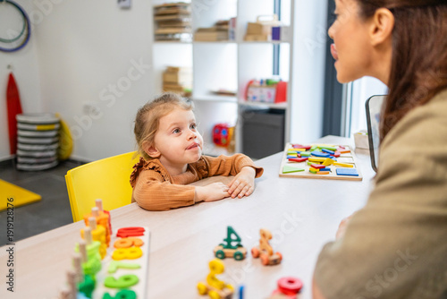 Speech therapist working with a young child on speech development, improving articulation and communication skills through playful educational exercises in a classroom setting