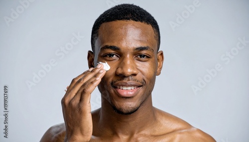 Man Applying Moisturizer to Face Smiling Healthy Skin Skincare Routine Confident Black Man Wellbeing Grooming Isolated.