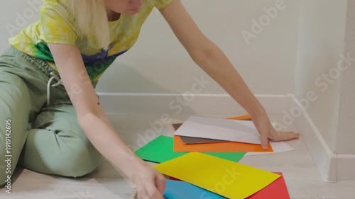 Adult woman in colorful loungewear choosing pastel cardstock for DIY craft at home