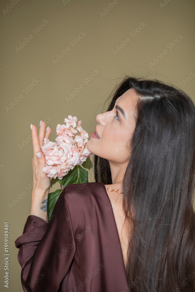 Naklejka premium A beautiful girl in a chocolate dress smiles and poses with fresh flowers