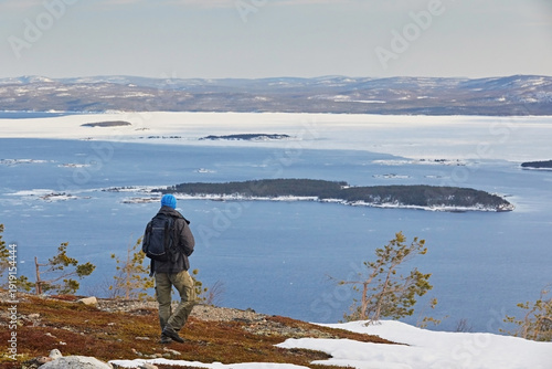Tableau sur toile A tourist walks through the tundra overlooking a sea of ​​ice floes