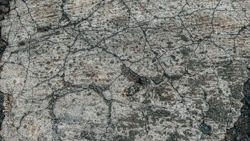 Close-up abstract texture of weathered concrete with fine cracks and grit, sh...