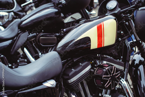 фотографія A close-up horizontal shot of a black motorcycle gas tank featuring a stylish cream and red striped graphic