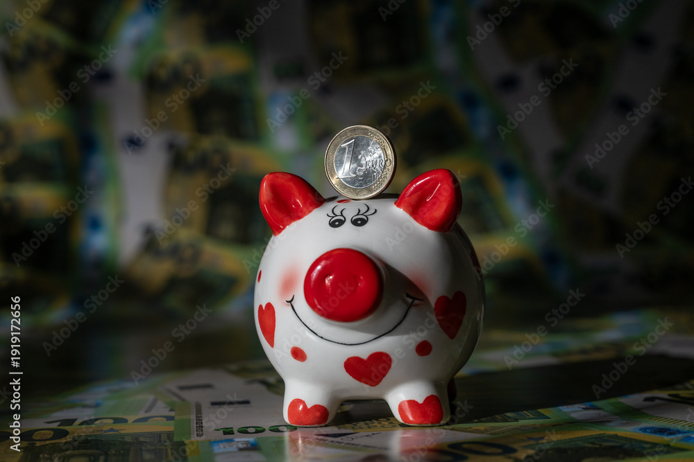Obraz premium A piggy bank against a background of 100 euro bills in a light and shadow pattern