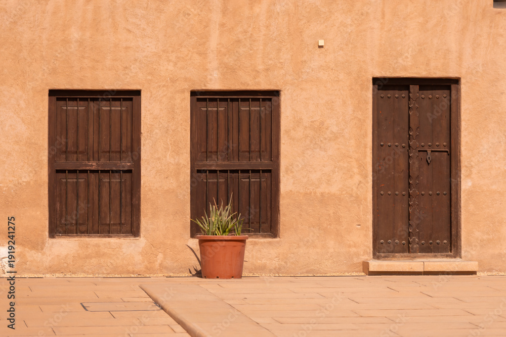 Obraz premium Views of Oriental buildings, sandstone walls and arches, windows and doors. On the streets of Dubai, in a public place.