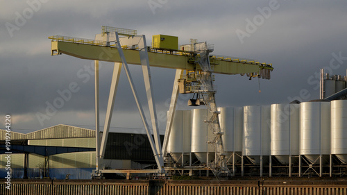 Foto large yellow gantry crane at an industrial port facility next to white silos