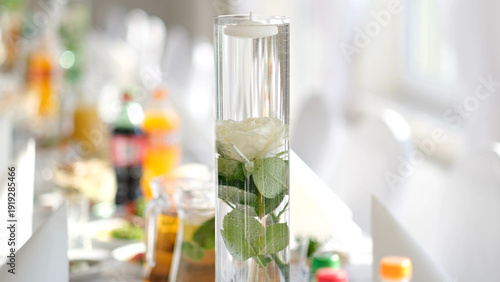 Foto Elegant glass vase with a submerged white rose and floating candle as a centerpi