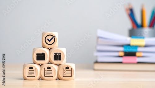 Pyramid of Wooden Blocks with Office Icons on a Desk with Blurred Stationary Background