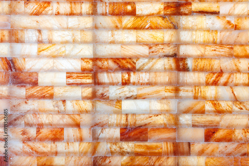 Close up of Himalayan pink salt brick wall background with natural orange and white textures for spa and wellness interior.