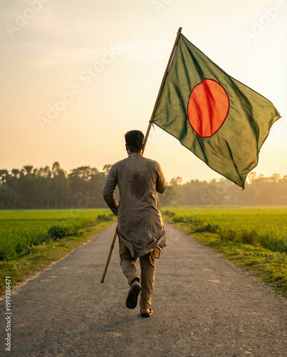 Man walking on a rural road holding the flag of Bangladesh at sunset, celebrating national pride.