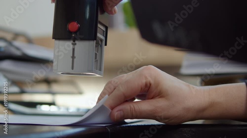 Stamping documents on stack of paperwork at office desk