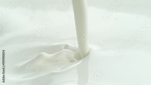 Pouring Creamy Lotion into White Milky Liquid Making a Splash and in Macro and Slow Motion