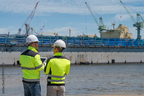 Quadro em tela An engineer works at a busy shipping port, inspecting containers and managing logistics operations, ensuring smooth import and export processes with safety and efficiency in global trade