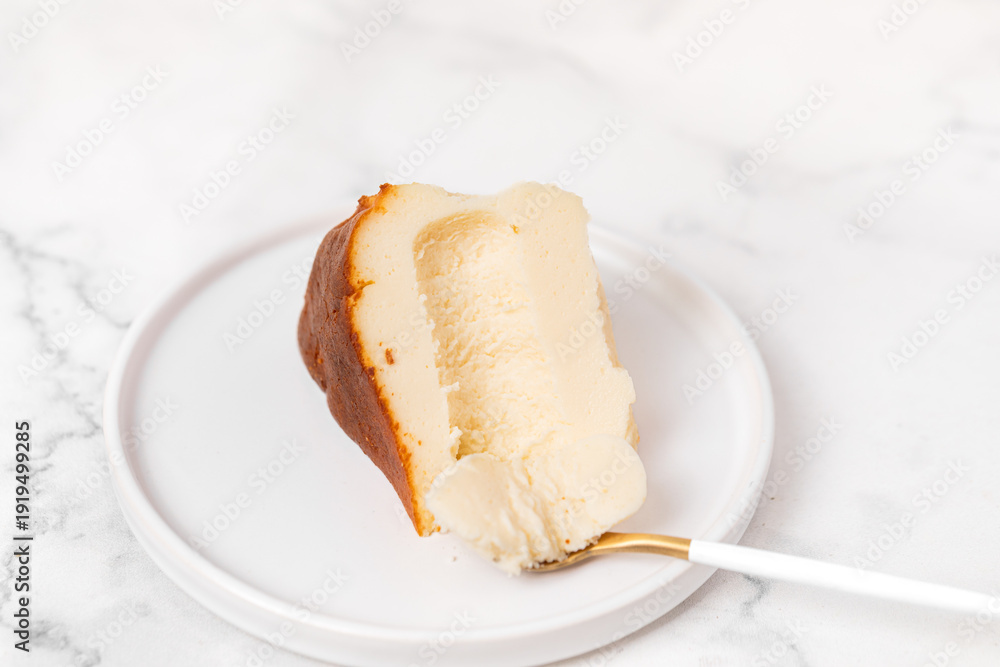 Fototapeta premium Creamy Cheesecake Slice on White Plate with Marble Background, San Sebastian cheesecake, Basque cheesecake