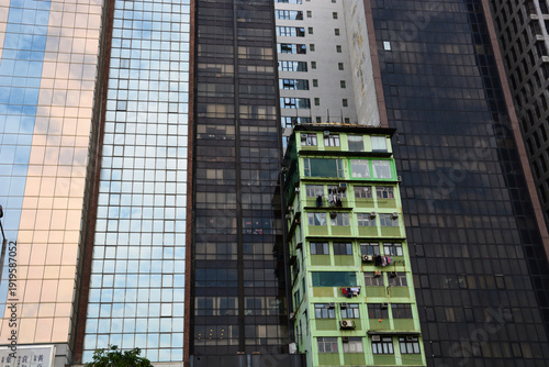 A holdout green apartment building is surrounded by new glass towers as the trendy Hong Kong neighborhood of Wan Chai undergoes gentrification .