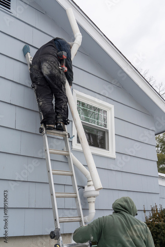 Bild auf Leinwand manual worker installing radon mitigation system outside the house