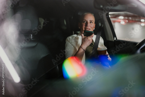 Slika na platnu Woman driving car at night, dictating message on smartphone, communicating while