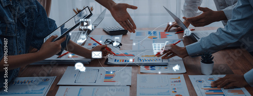 Obraz na plátne Diverse hands engage over charts and devices in a modern office setting, representing collaboration in business strategy and data analysis for growth and success