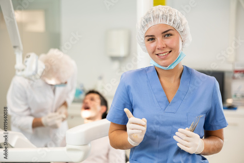 Foto Young girl doctor in blue suit cooperates with clinic, works as general practitioner in dental department of clinic