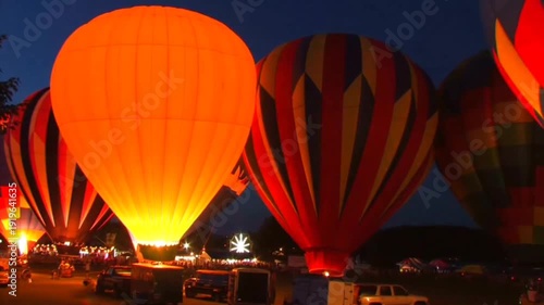 Hot air balloons glowing at night during balloon festival with illuminated burners and crowds