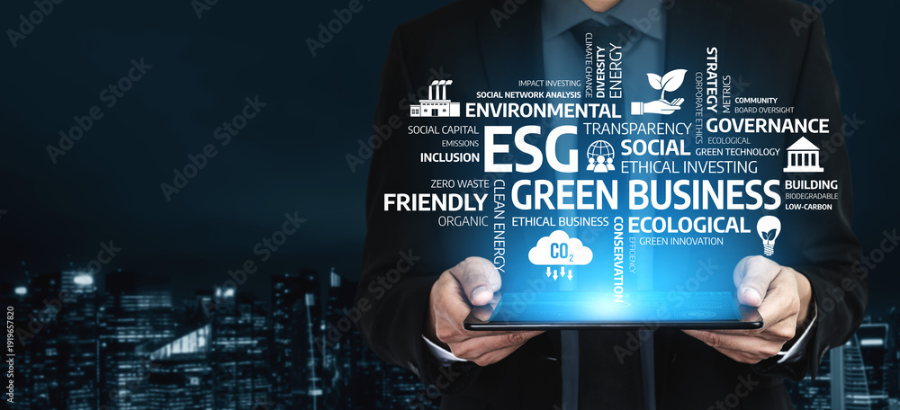 Fototapeta premium A businessman stands against a cityscape at night, holding a tablet displaying concepts of ESG, sustainability, and corporate responsibility, emphasizing modern business strategies. Tessel