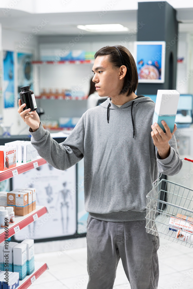 Φωτογραφία Asian man with shopping basket inspects health supplements in neighborhood pharmacy