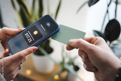 A person uses a smartphone to make a contactless payment with a card.
