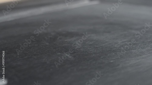 Hand writing with white chalk on a dark chalkboard surface